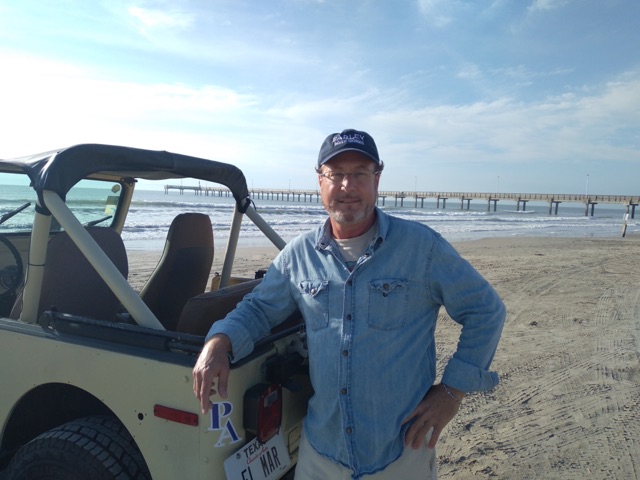 William L. Foster II — Port Aransas REALTOR® and host of PortABeachLife.fun, standing beside a vintage Jeep on the beach with Horace Caldwell Pier in the background
